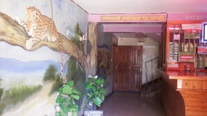 A reception area with a leopard mural, a wooden reception desk, and a sign indicating a slippery floor.