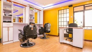Un salón de belleza con dos sillas negras, una barra blanca y estantes con productos para el cabello.