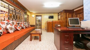 Un vestíbulo de hotel con un sofá, un escritorio de madera y una televisión.