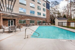 A hotel pool area with a stone facade, outdoor seating, and a lifeguard station.