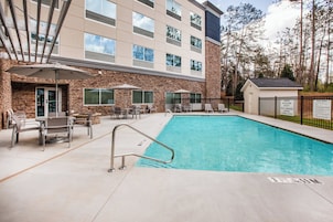 A hotel pool area with a stone facade, outdoor seating, and a lifeguard station.