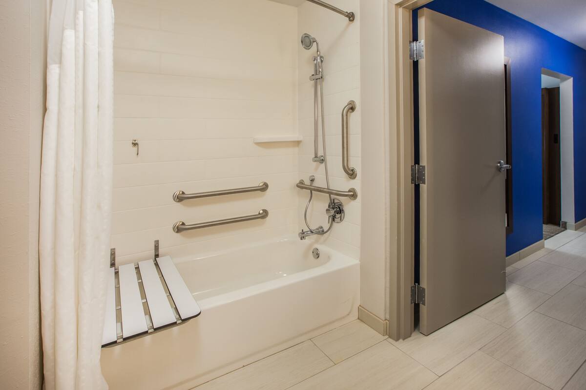 A modern bathroom with a walk-in bathtub, grab bars, and a shower head.