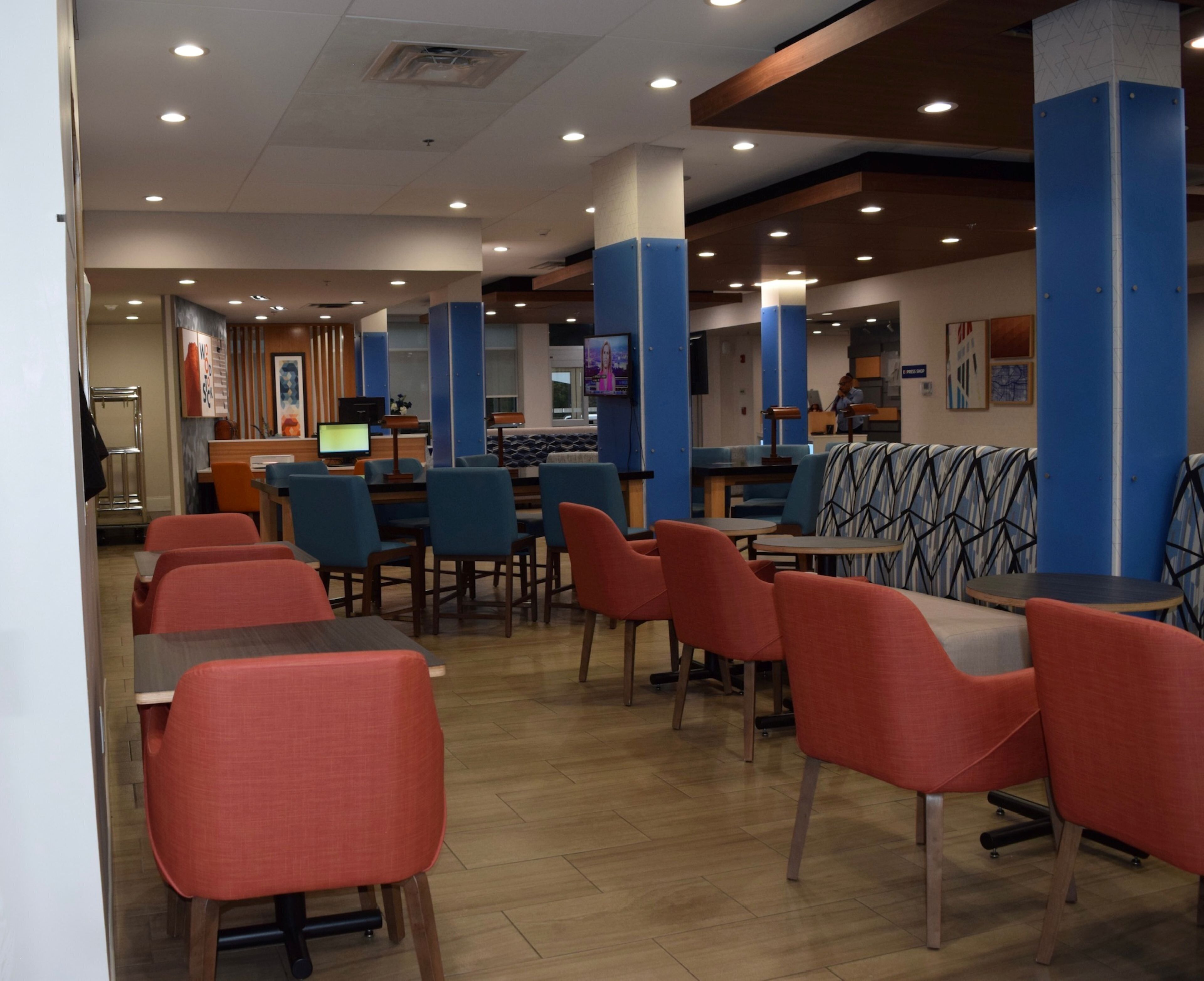 A modern restaurant with red and blue seating, a counter area, and a television screen.