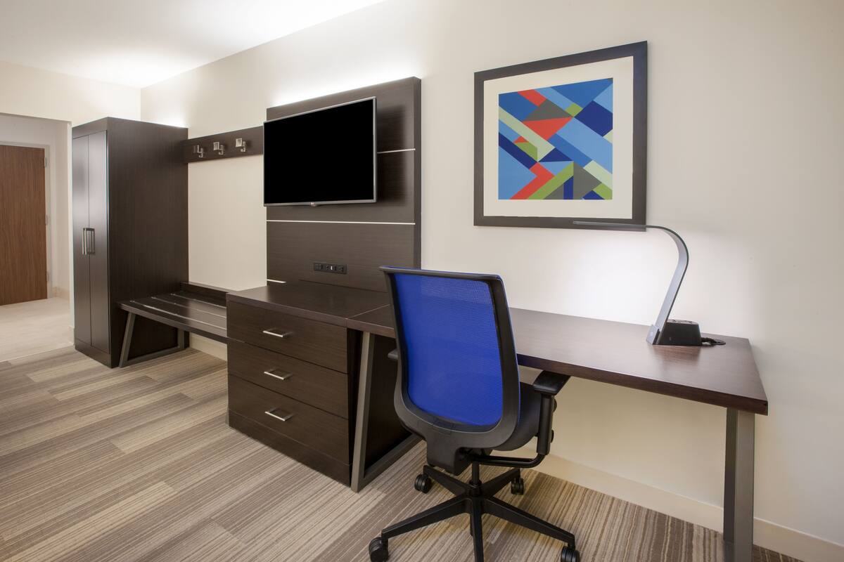 A modern office space with a desk, chair, and built-in TV.