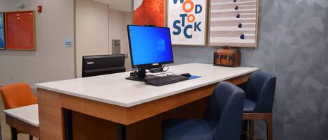 A reception desk with a computer, a sign indicating maximum occupancy, and framed artwork on the wall.