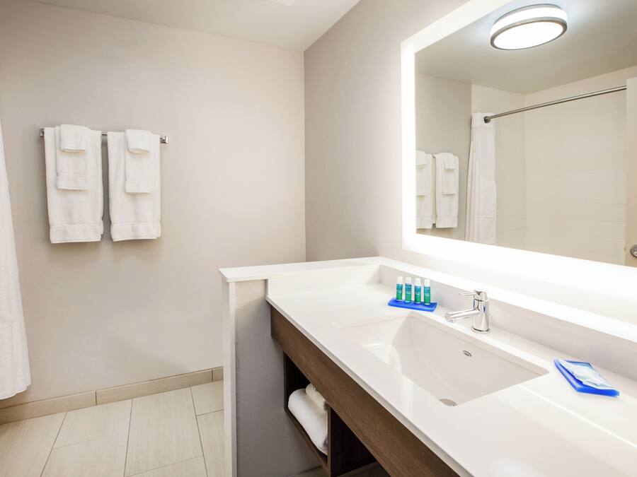 A bathroom with a white sink, a mirror, and two white towels hanging on a towel rack.