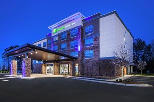 Edificio Holiday Inn Express con fachada de piedra, un acceso cubierto y un estacionamiento.