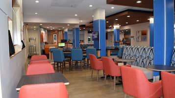 A restaurant with booths and tables, a counter, and a television screen.