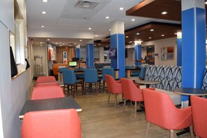 Un restaurant avec des banquettes et des tables, un comptoir et un écran de télévision.