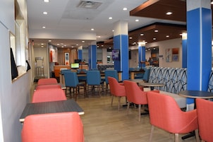 Un restaurante con mesas, cabinas y una barra, y una pantalla de televisión.