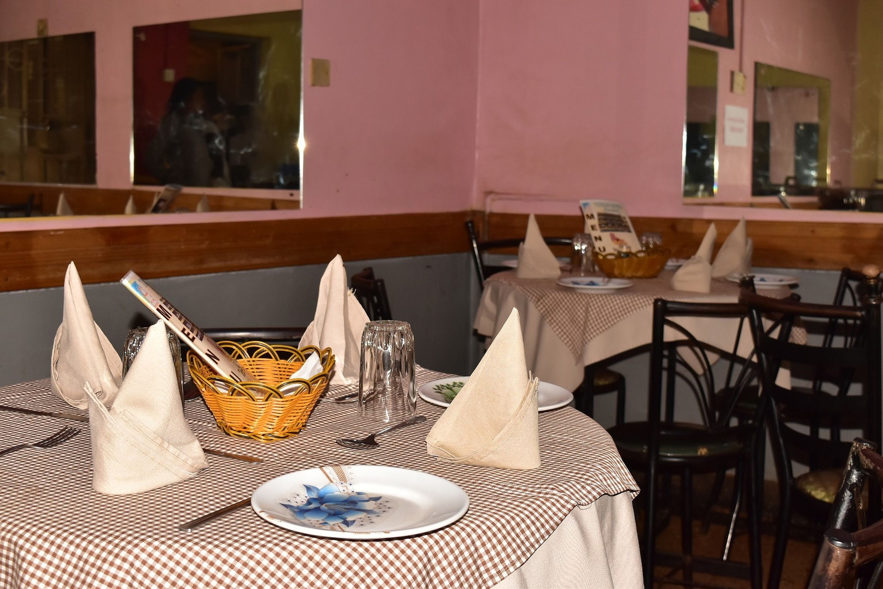 A restaurant with checkered tablecloths, neatly set tables with napkins, and wicker baskets.