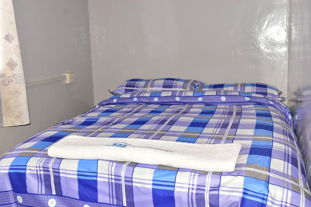 A bed with a blue and white checkered bedspread, a white pillow, and a white blanket.