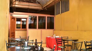 A restaurant with multiple round tables and chairs, a red tablecloth, and a wooden interior. - Tickles Hotel (Nyeri)
