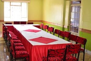 A conference room with a long table, red chairs, and a green accent wall. - Tickles Hotel (Nyeri)