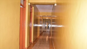 A long, narrow hallway with patterned floor tiles and yellow walls. - Tickles Hotel (Nyeri)