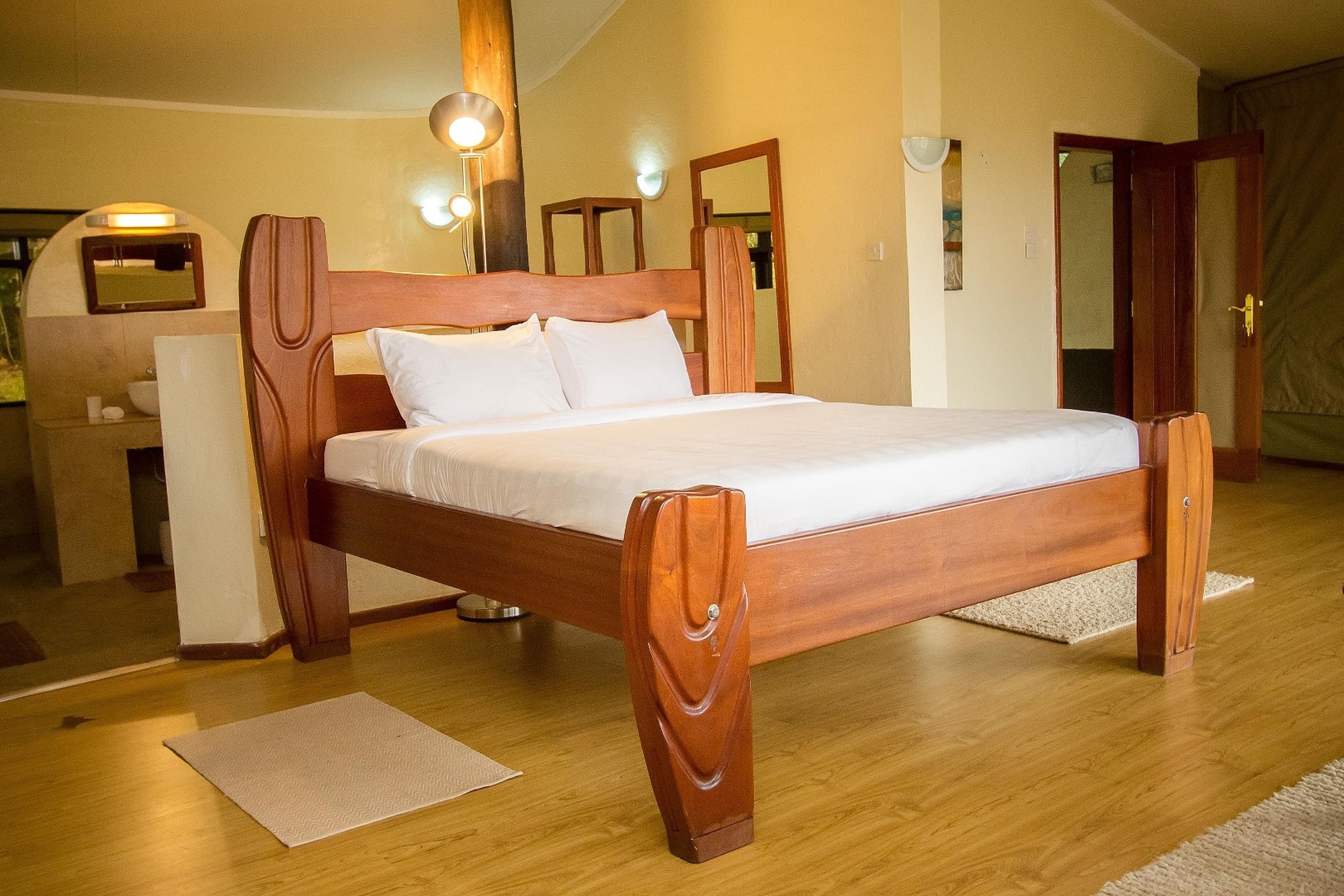 Een houten bed met hoofdbord, nachtkastje en spiegel.