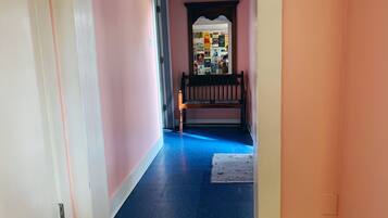 A hallway with pink walls, a wooden bench, and a blue floor.