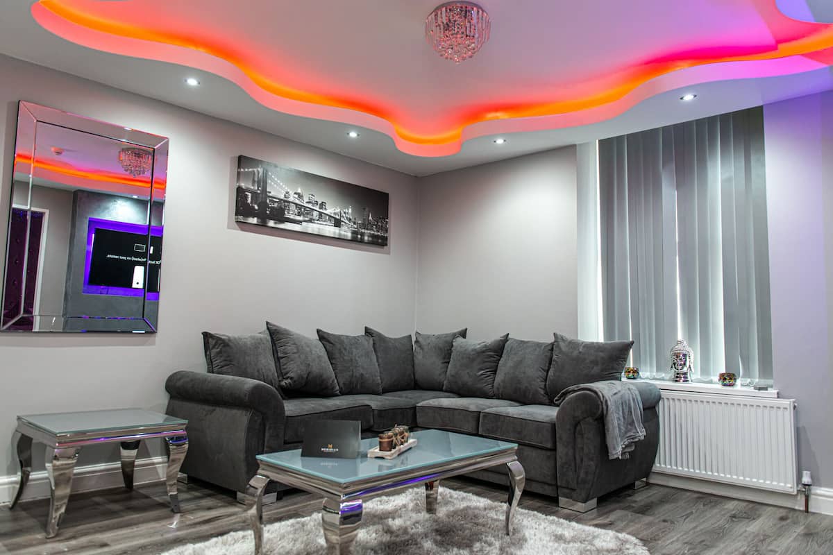 A modern living room with a sectional sofa, a glass coffee table, and a mirrored wall.