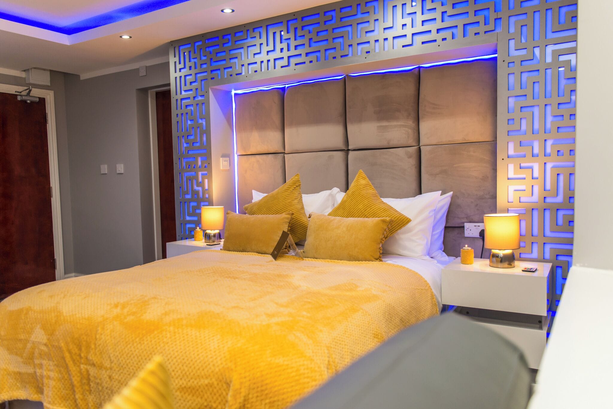 Ein Hotelzimmer mit einem großen Bett, zwei Nachttischen mit Lampen, einer dekorativen Wandverkleidung und einem modernen Deckenbau.