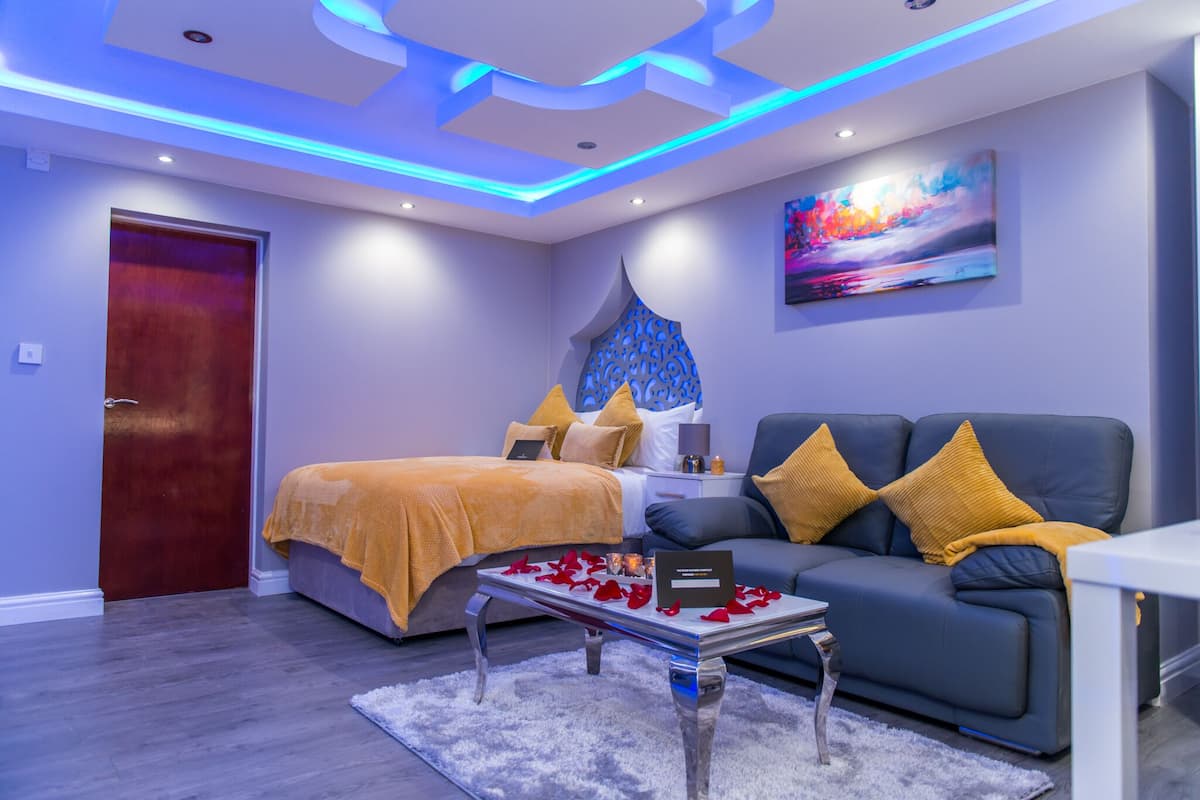 A modern bedroom with a bed, a sofa, a coffee table, and a painting on the wall.