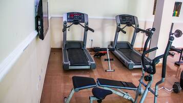 A gym with treadmills, a bench, and weight equipment.