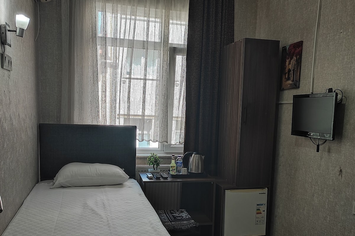 Ein Hotelzimmer mit Bett, Schreibtisch, Fernseher und einem fenster mit Vorhängen.