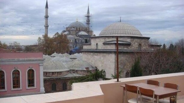 Une terrasse avec une table et des chaises, offrant une vue sur des bâtiments historiques dotés de coupoles et de minarets.