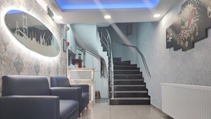 Un hall d’entrée avec un escalier, un espace détente et un comptoir d’accueil.
