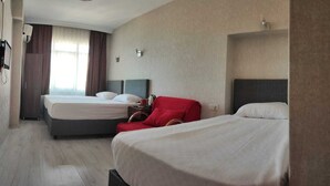 Une chambre d’hôtel avec deux lits, une chaise rouge et une petite table avec une lampe.