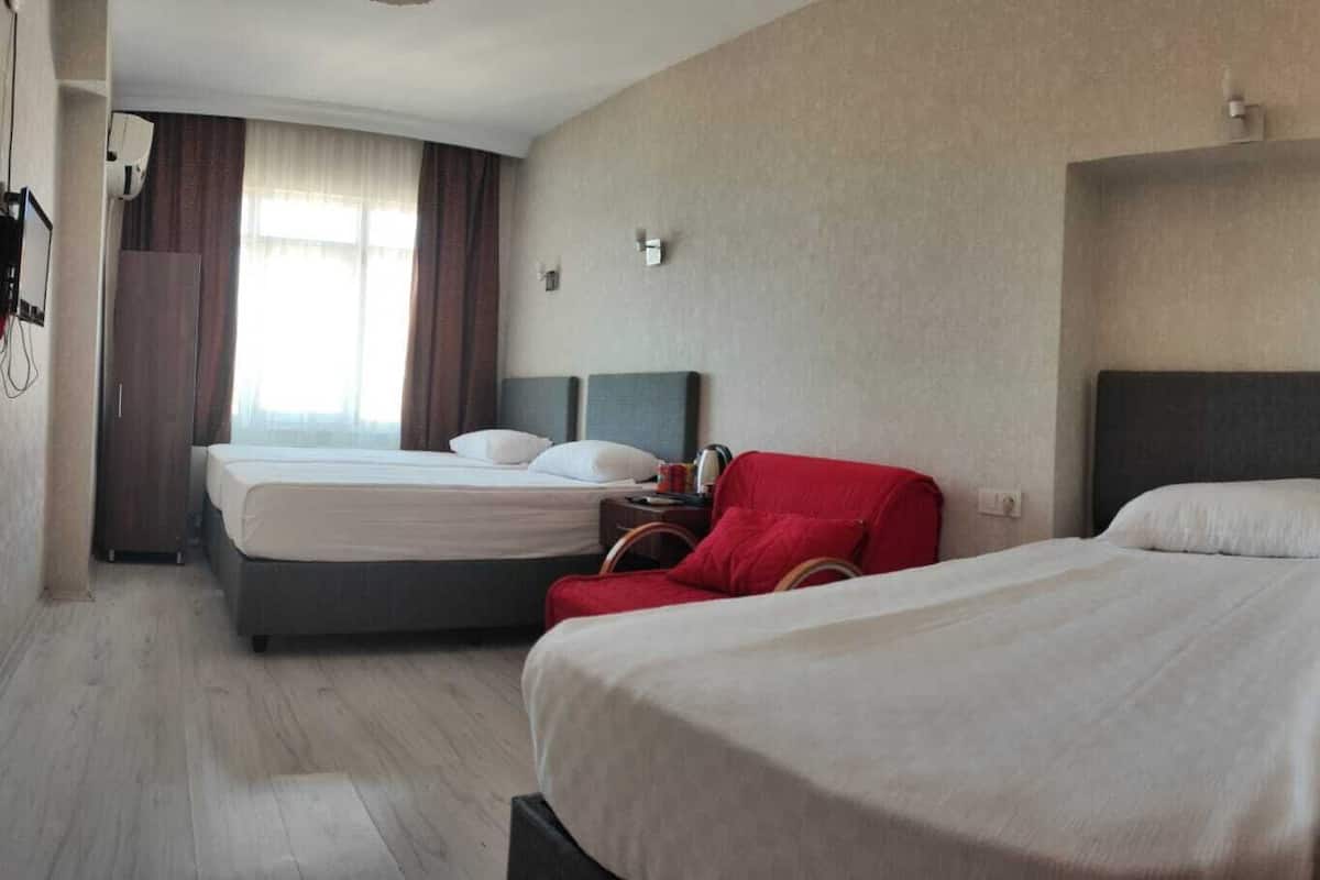 Ein Hotelzimmer mit zwei Betten, einem roten Sessel und einem kleinen Tisch mit einer Lampe.