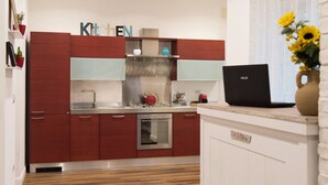 Una cucina moderna con mobili rossi, forno integrato e un portatile sul piano di lavoro.