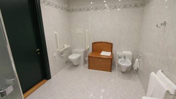 A modern bathroom with a toilet, bidet, and a wooden cabinet.