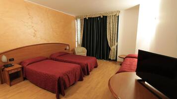 Una habitación de hotel con dos camas, un televisor, una mesita y una silla.