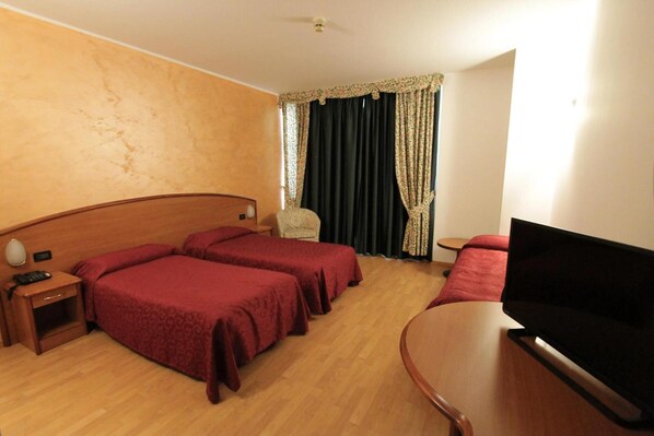 Una habitación de hotel con dos camas, un televisor, una mesita y una silla.