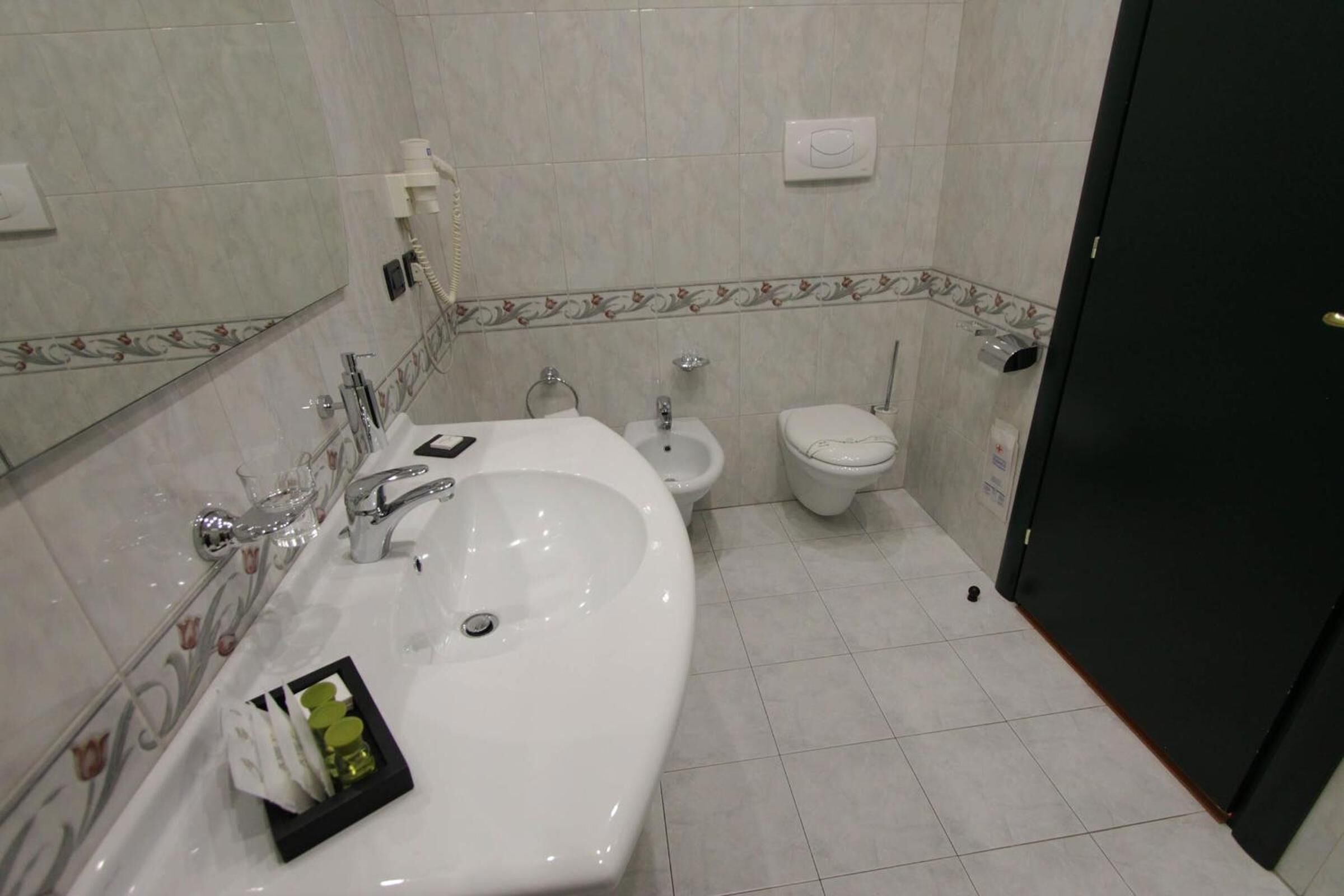 Une salle de bain équipée d’un lavabo, d’un bidet, de toilettes et d’un miroir.
