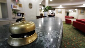 A hotel reception desk with a brass bell and a marble counter. - Hotel Europa (Biella)