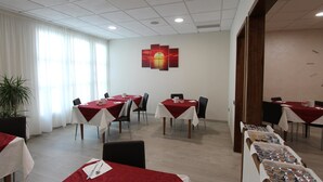 A conference room with tables set for meetings, a large window with curtains, and a wall-mounted artwork. - Hotel Europa (Biella)