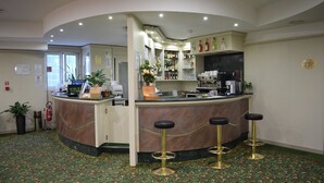 A hotel lobby with a reception desk, bar area, and a patterned carpet. - Hotel Europa (Biella)
