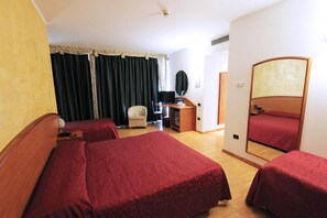A hotel room with two beds, a desk, a chair, a television, and a mirror. - Hotel Europa (Biella)
