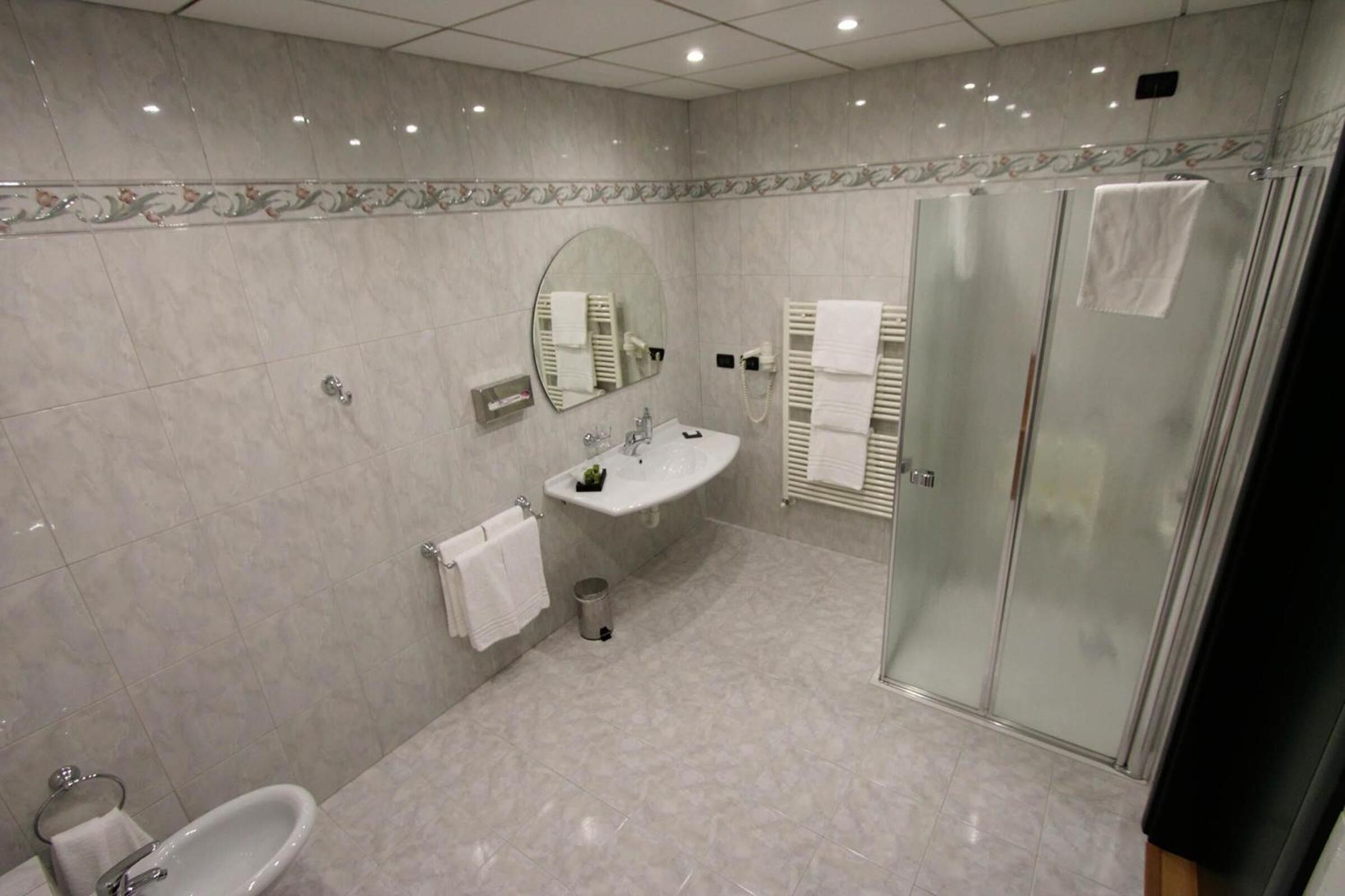 A modern bathroom with a glass shower enclosure, a sink with a mirror, and a bathtub.