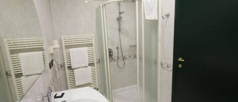 Un baño moderno con ducha de vidrio, un lavabo blanco y una puerta negra.