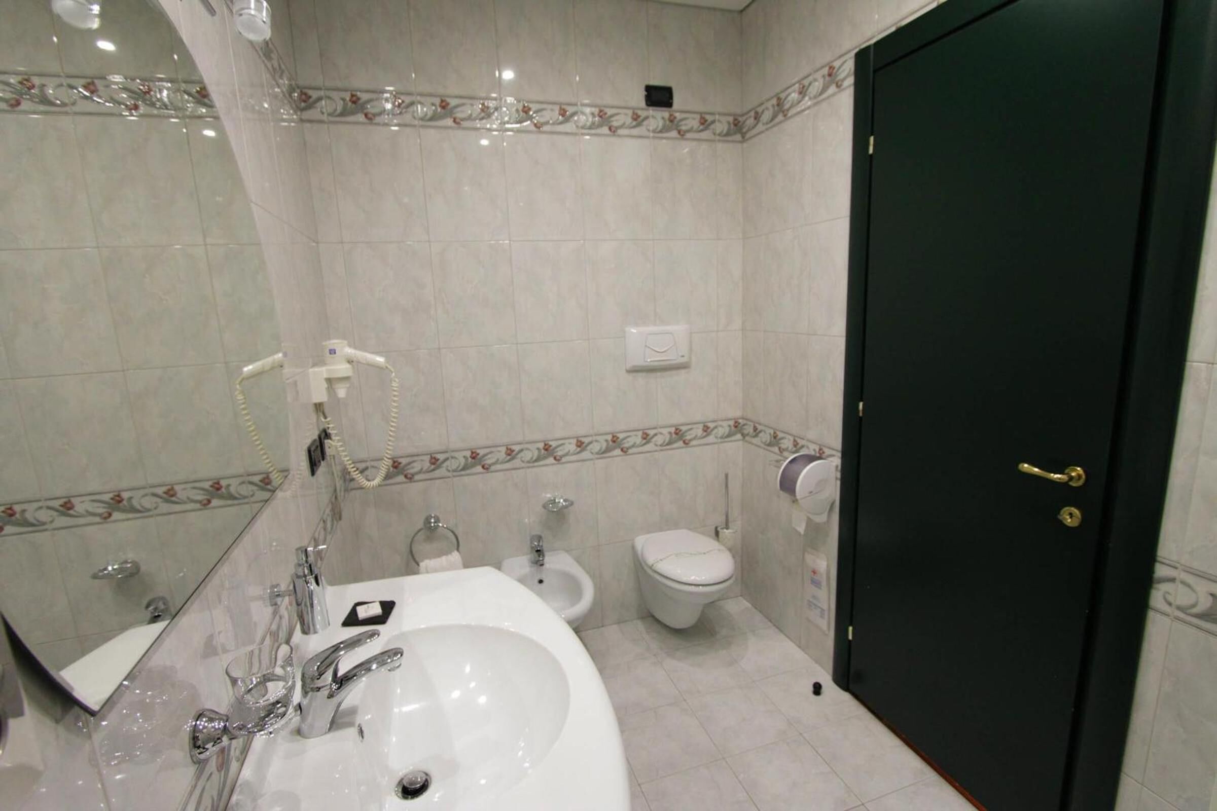Un baño con lavamanos, espejo, inodoro, bidé y una puerta.