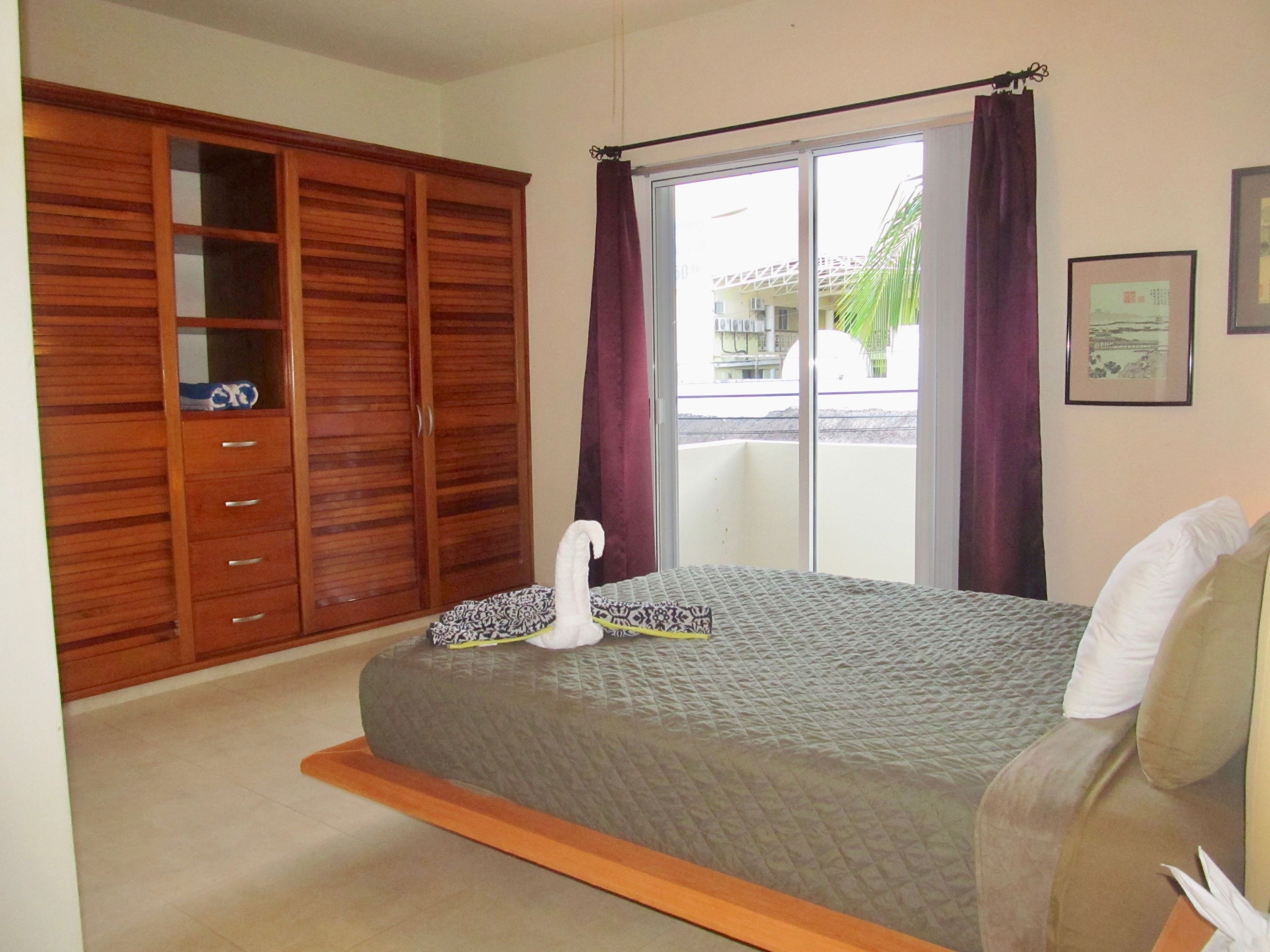Une chambre à coucher avec un lit, une armoire et une fenêtre avec des rideaux.