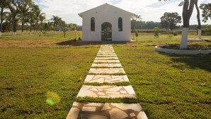 A pathway leading to a white building with arched windows, surrounded by grass and trees, under a clear sky. - Ramada by Wyndham Furnaspark (Formiga)