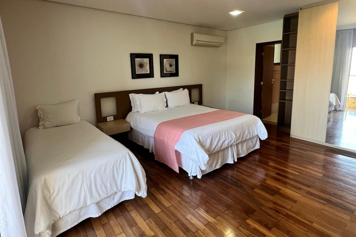Habitación de hotel con dos camas, suelo de madera, ventilador de techo y aire acondicionado.