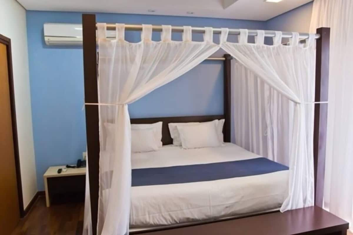 Un dormitorio con cama con dosel, una mesita de noche y un velador.