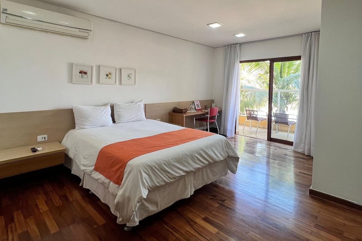 Habitación de hotel con cama, escritorio, silla y un amplio ventanal.