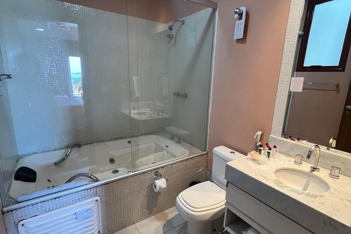 Un baño moderno con ducha de vidrio, inodoro, lavabo con espejo y bañera.