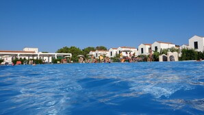 A swimming pool area with people, white buildings, and a clear blue sky. - Blumare Hotel & Residence (Otranto)