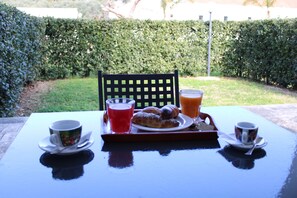 A table with breakfast items including croissants, juice, and coffee, set outdoors with a hedge in the background. - Blumare Hotel & Residence (Otranto)
